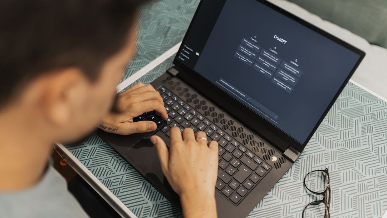 Answer engine optimisation: a man working on a laptop with AI software open on the screen, wearing eyeglasses