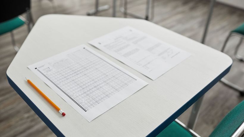 A close-up image of an exam paper and pencil on a classroom desk, ready for a test