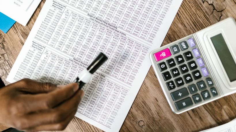 Close-up of tax documents and calculator on wooden table, highlighting financial analysis
