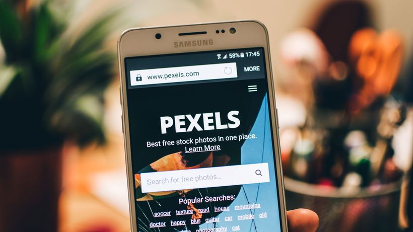 A close-up view of a smartphone displaying the Pexels website screen for stock photo searches
