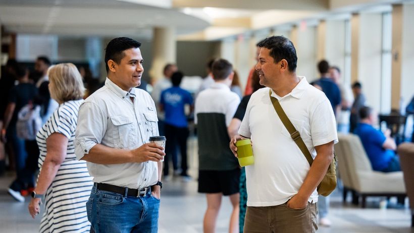 Two adults engaging in casual conversation during an indoor networking event