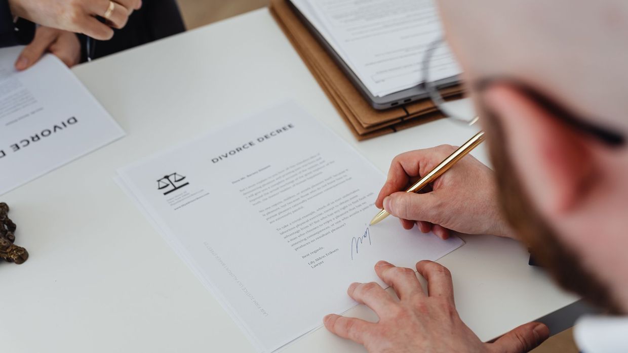 Advertising disclosure: close-up of a person signing a divorce decree on a desk