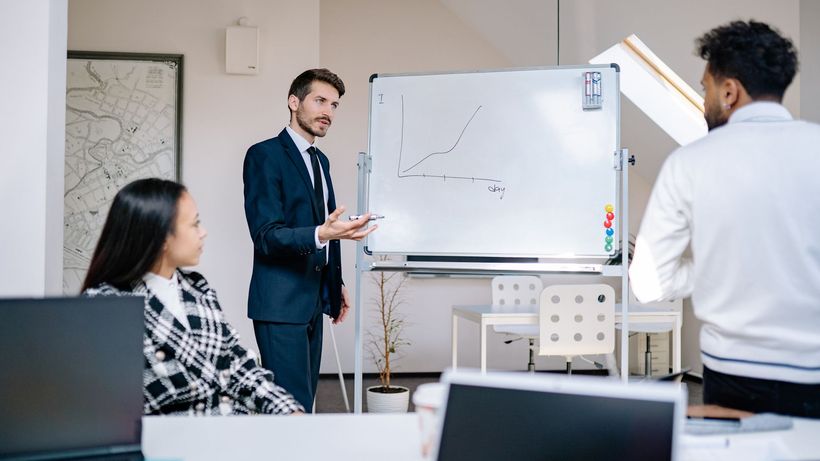 Business team in office presenting growth graph on a whiteboard for strategy discussion and teamwork insights