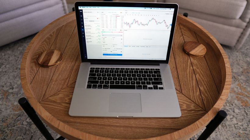 Close-up of a laptop displaying trading charts on a stylish wooden table, ideal for financial themes