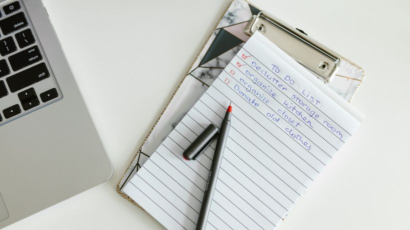A neatly organized to-do list on a clipboard next to a laptop and pen, conveying productivity