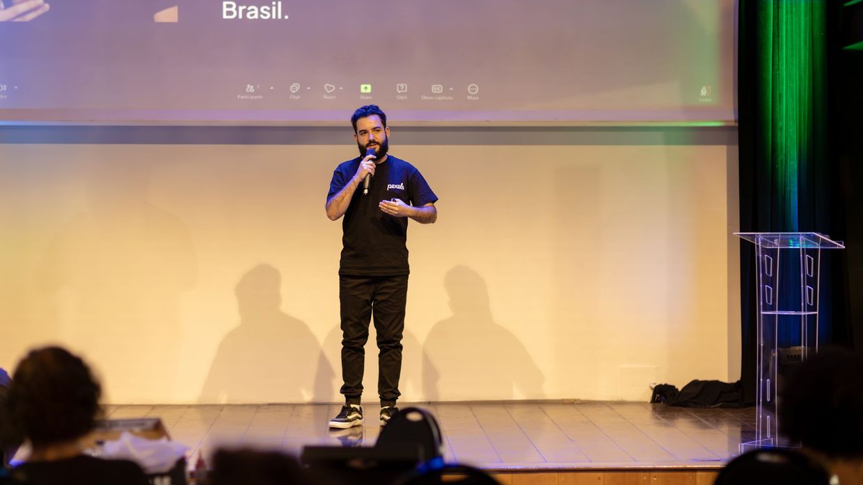E-E-A-T: man speaking on stage with a microphone at a conference in Brazil