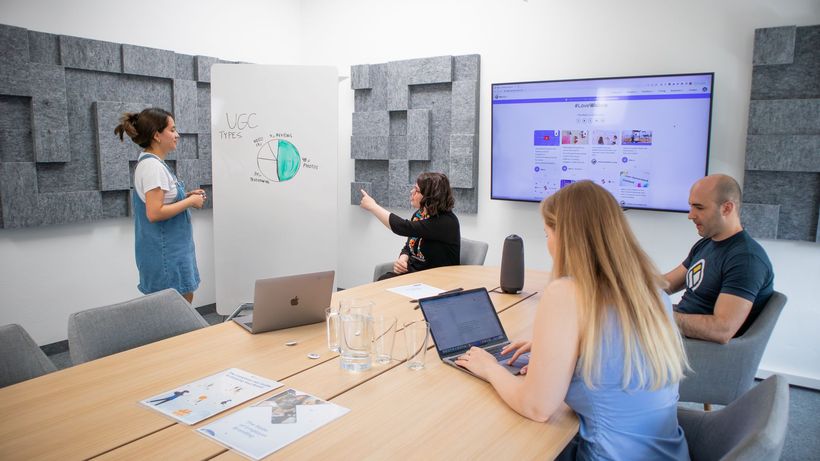 A group of professionals engaged in a team meeting with a presentation in a modern office setting