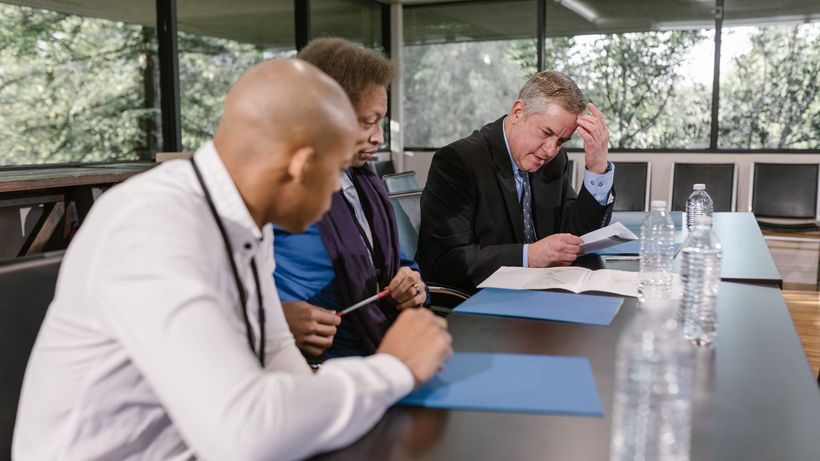 Group of diverse colleagues in a business meeting reviewing documents indoors