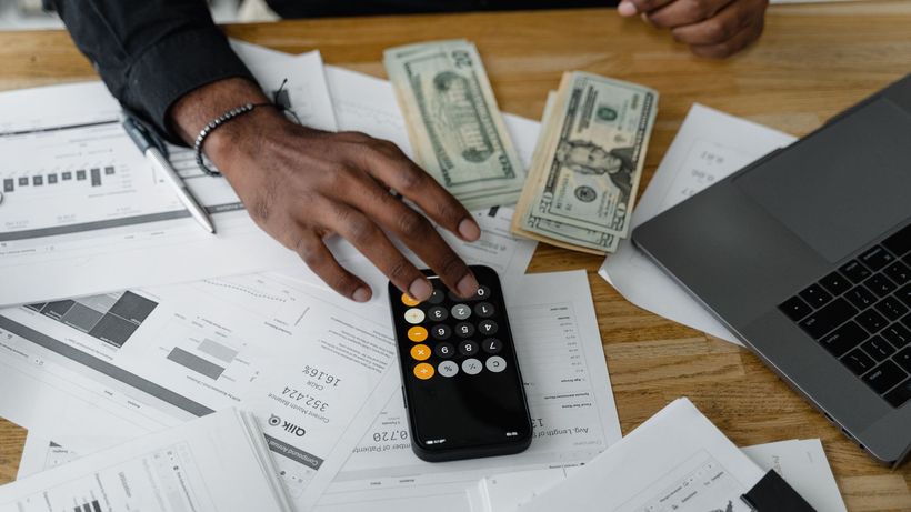 Overhead view of financial documents with calculator, cash, and laptop for financial planning