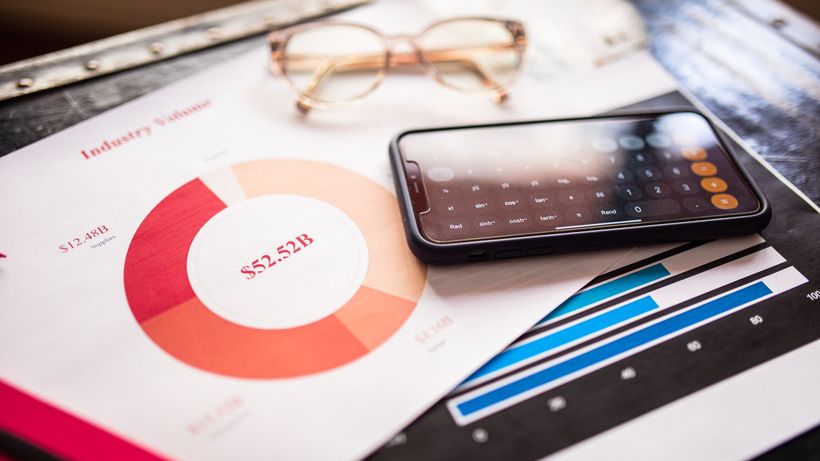 Smartphone on business documents with charts and graphs, illustrating financial analysis