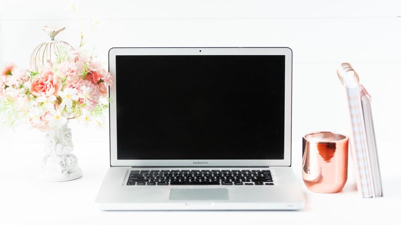 A sleek workspace featuring a laptop, floral arrangement, and copper mug for a modern aesthetic