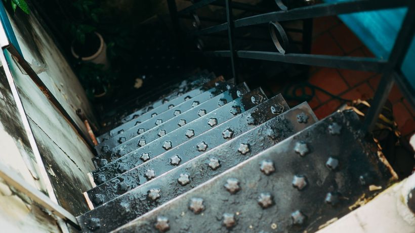 Close-up view of a wet and rustic metal staircase with star-shaped grips