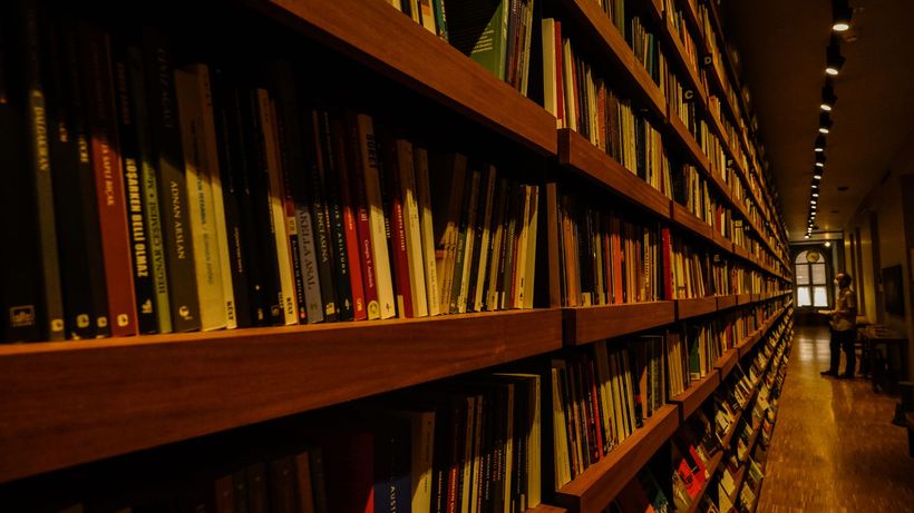 Long shelves filled with books in a warmly lit library interior, ideal for reading enthusiasts