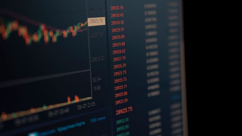 Close-up of a computer screen showing dynamic financial market data and charts, indicating real-time trading updates