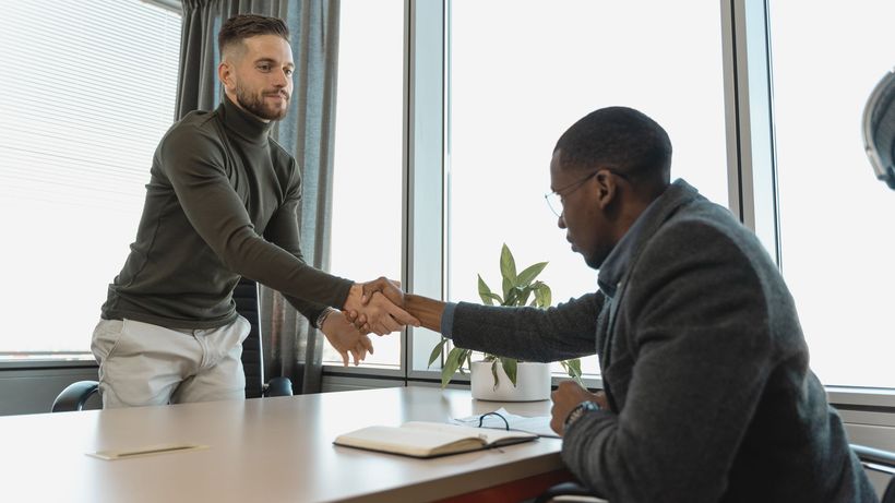 Two businessmen shaking hands in a modern office after a successful meeting or interview