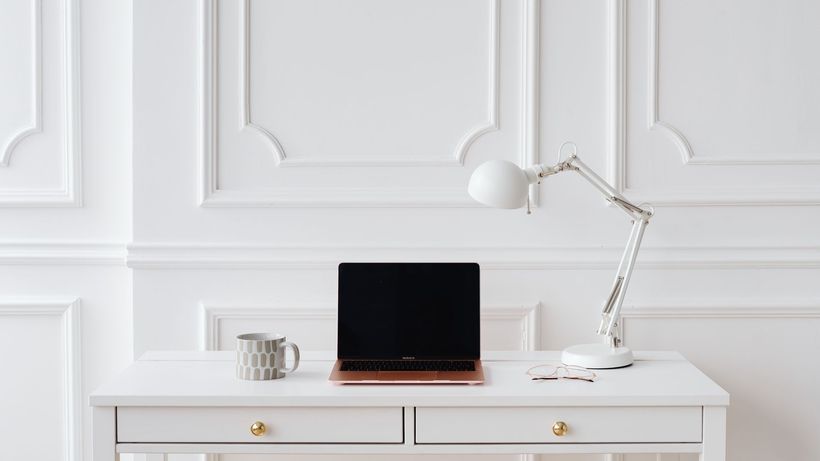 Elegant minimalist workspace with laptop and desk lamp on a white desk in a bright room