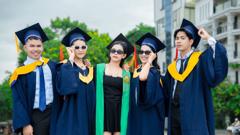 Group of young Cambodian graduates celebrating their university graduation outdoors in Battambang