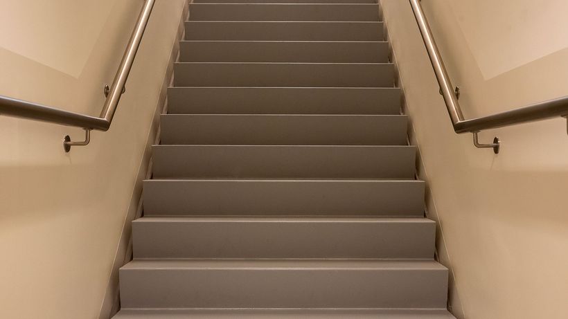 A beige indoor staircase with metal railings, showcasing symmetry in a minimalist design
