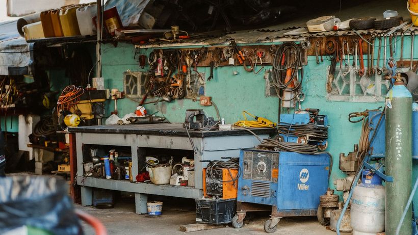 A cluttered workshop with tools, welding equipment, and storage solutions
