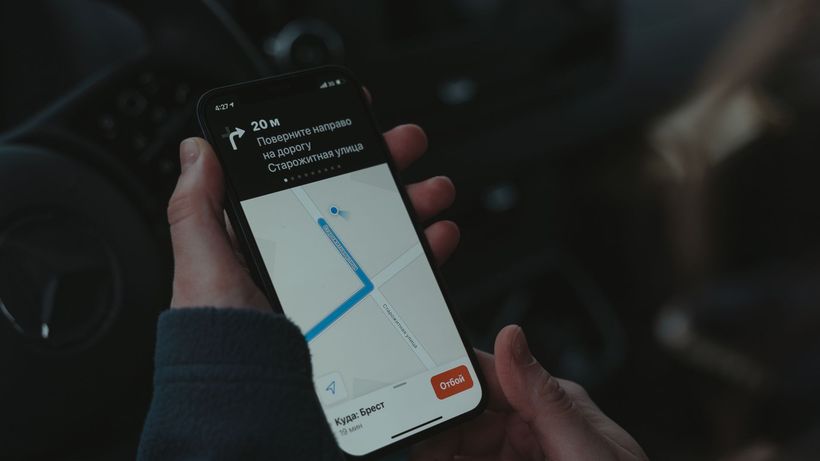 Close-up of a smartphone displaying a navigation app in a car, highlighting modern technology use while driving