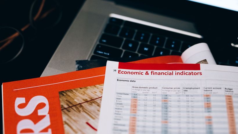 Detailed close-up of economic and financial documents on a laptop keyboard, highlighting data analytics