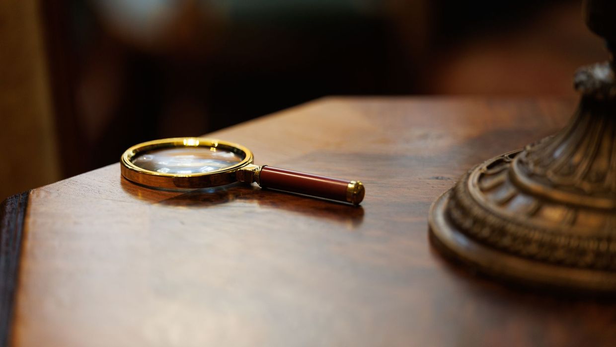 Keyword research: a vintage-style magnifying glass placed on a polished wooden table, exuding an elegant and classic look