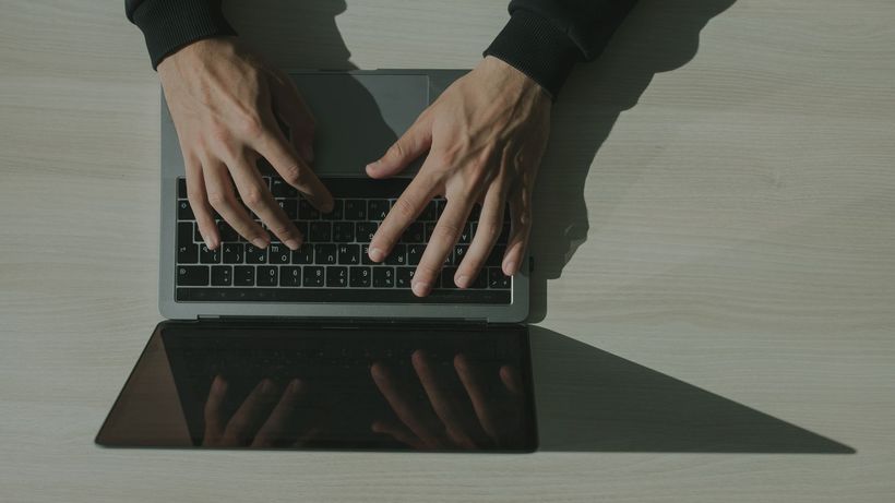 Overhead shot of hands typing on a laptop, showcasing technology and internet usage