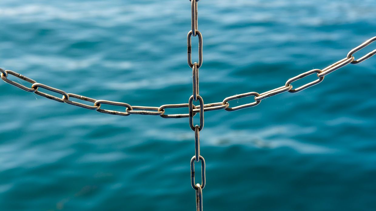 Link building skills: close-up of interconnected metal chains with the ocean blurred in the background