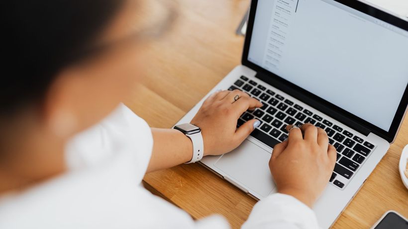 High angle shot of a person typing on a laptop, focused on hands and keyboard