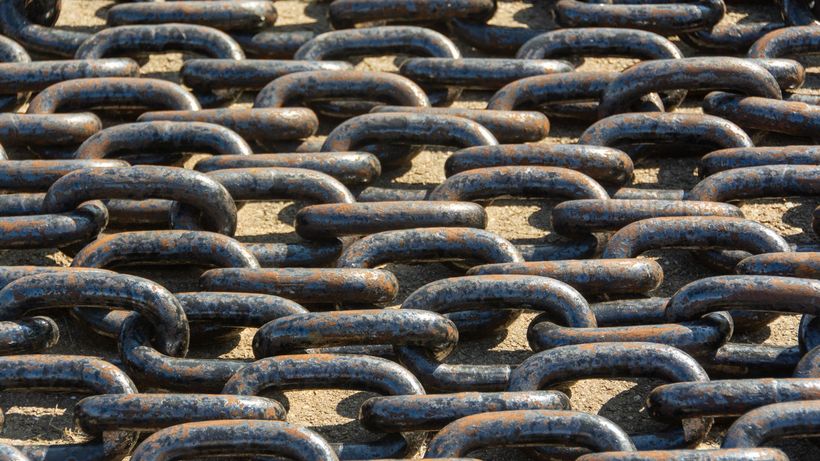 Detailed view of rusty metal chains arranged outdoors in sunlight