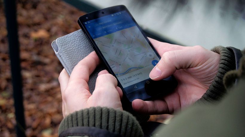 Close-up of hands using a map app on a smartphone outdoors, showcasing GPS navigation