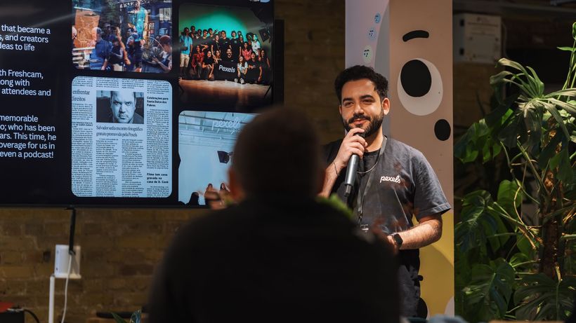 A speaker holding a microphone addresses an audience indoors at a presentation event