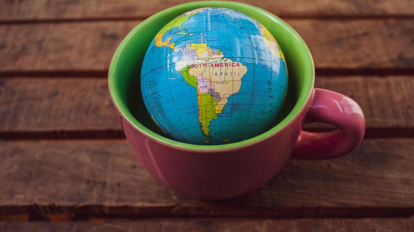 A vibrant globe inside a mug placed on a rustic wooden surface, symbolizing global travel