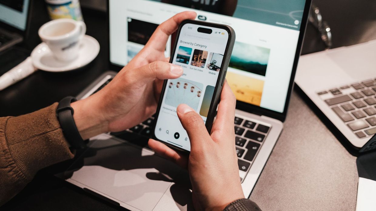 Search intent: close-up of hands using a smartphone over a laptop in a modern office environment