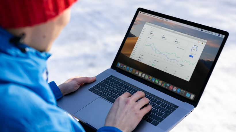 Person working on a laptop analyzing charts in an outdoor setting during winter