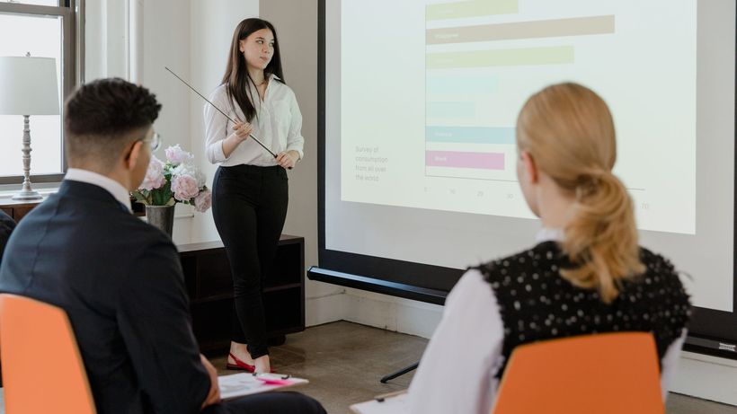 A young professional presenting data in a modern office to attentive colleagues