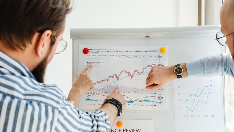 Colleagues discussing data trends on a whiteboard with graphs and charts