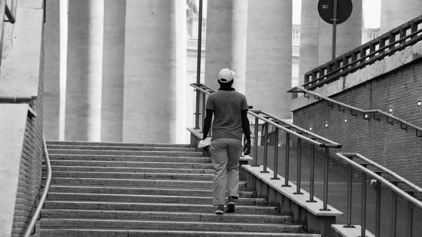 A person walking up an urban stairway captured in black and white, emphasizing structure