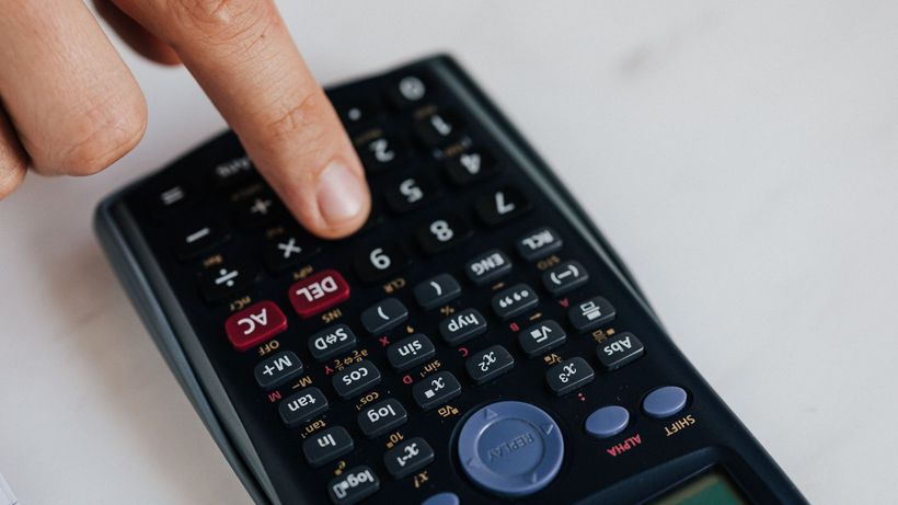 From above of crop anonymous economist calculating on calculator with plastic buttons while making budget on marble table