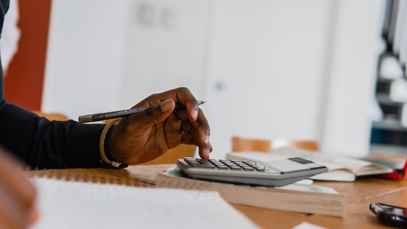 Close-up of a person using a calculator and pen for financial work at a desk