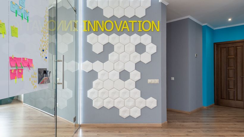 Geometric decoration on wall with Innovation inscription near glass door of conference room with colorful stickers