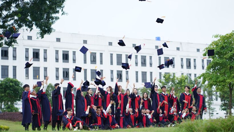 A group of graduates in Vietnam celebrate by throwing caps into the air