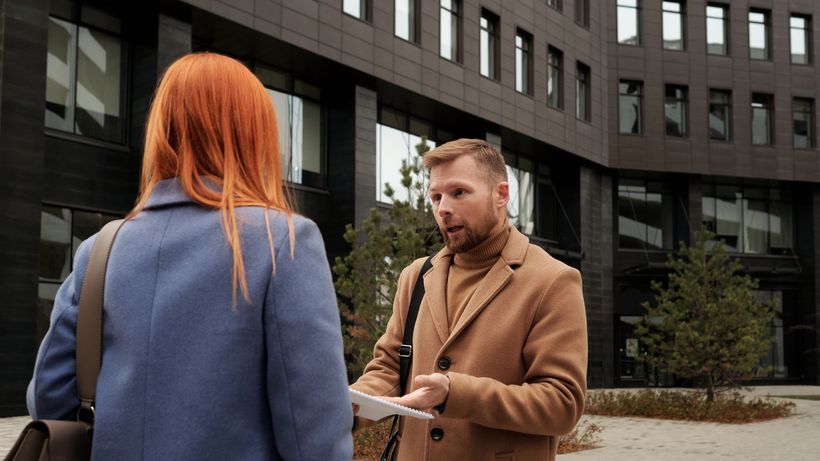Two business professionals in conversation outside an urban office building