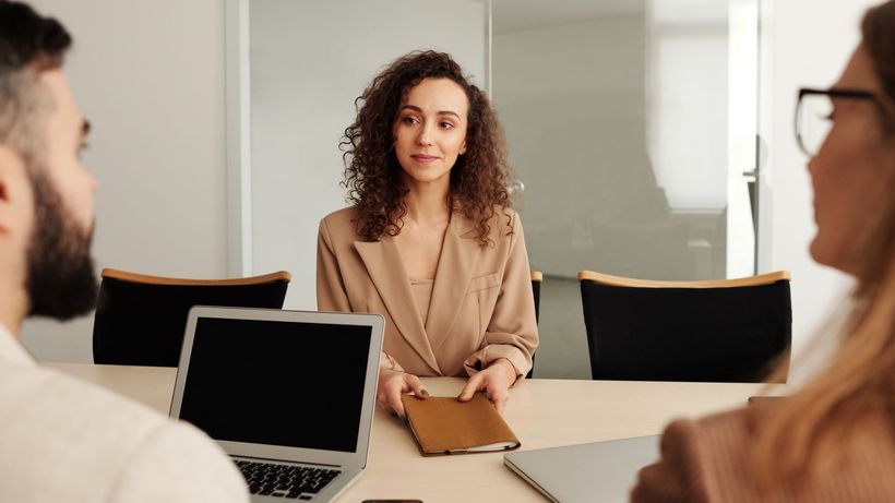A woman in a business suit participates in a job interview, showcasing professionalism and modern office environment