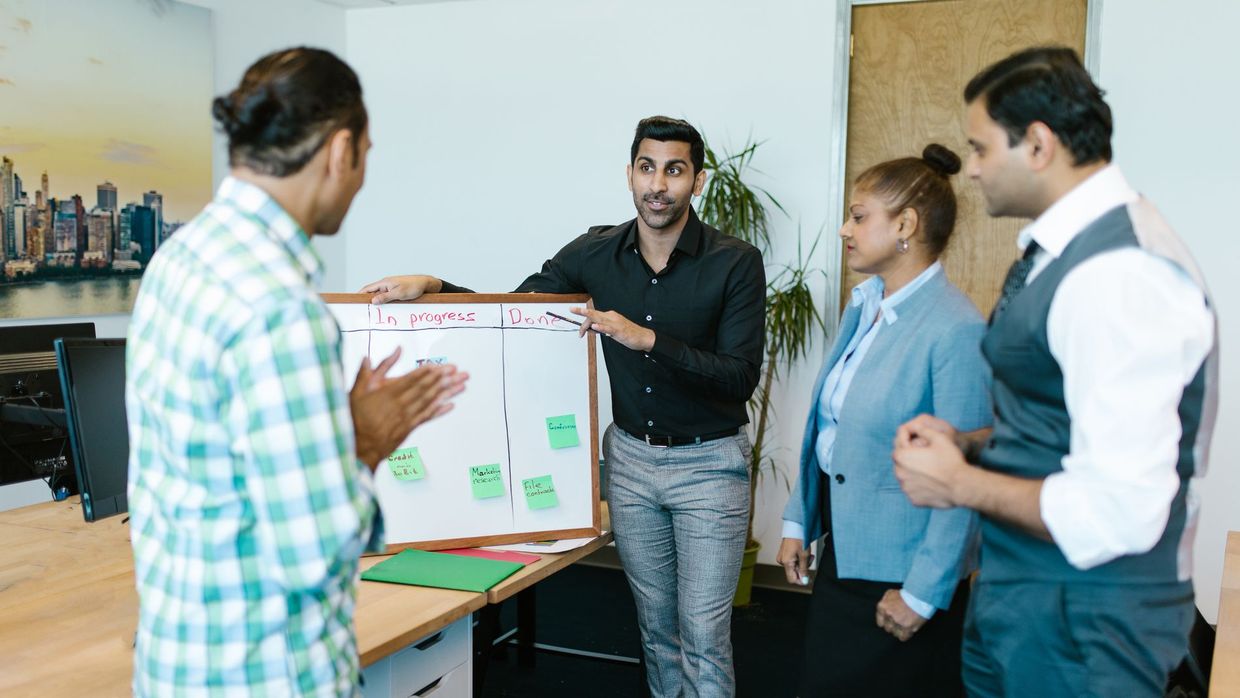 SEO manager pay and benefits: diverse team discussing project progress with a board in a modern office