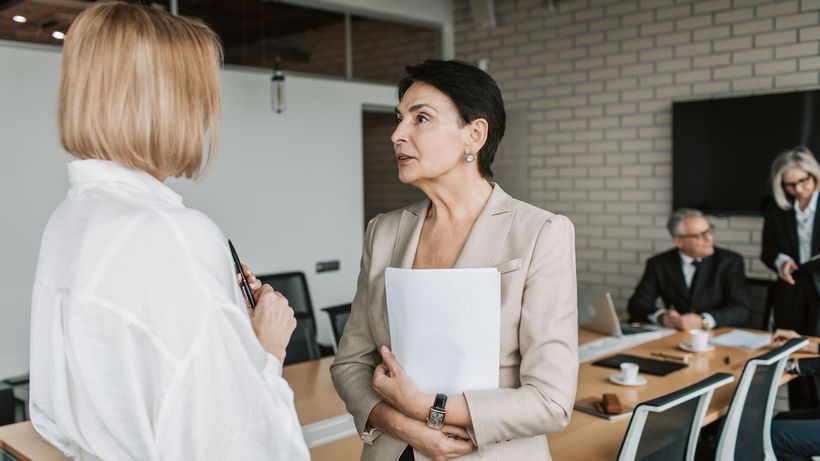 Two businesswomen engage in a conversation during a professional meeting in a modern office