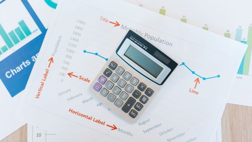 Calculator placed on financial graphs and reports showcasing data analysis and business documentation