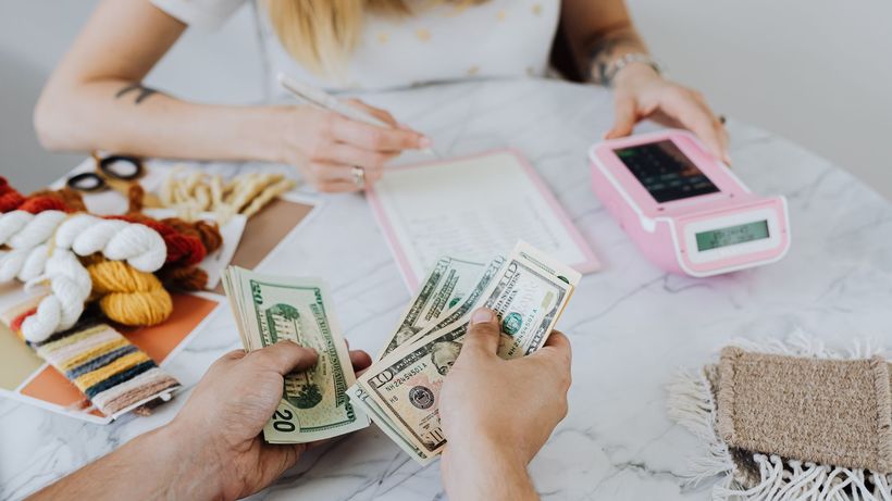 Two people handling cash and budgeting with a calculator and notebook at a table