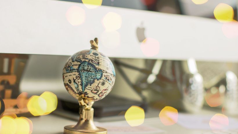 Close-up of a miniature globe on an office desk with a bokeh light effect, creating a dreamy atmosphere