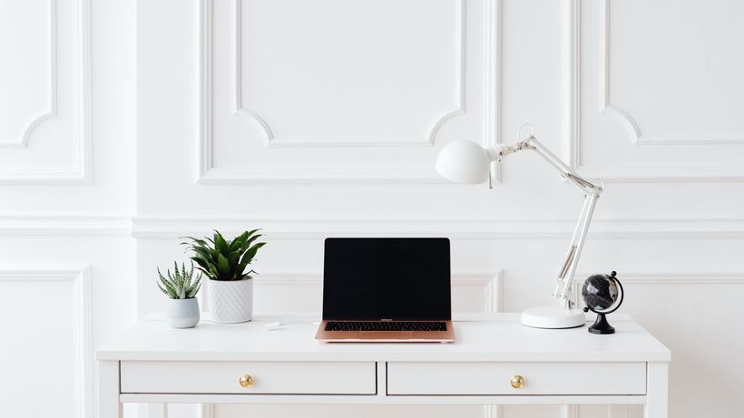 A minimalist home office setup featuring a laptop on a white desk with decor items